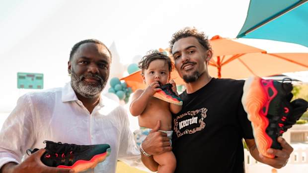 Trae Young alongside his father and son hold black and red adidas shoes.